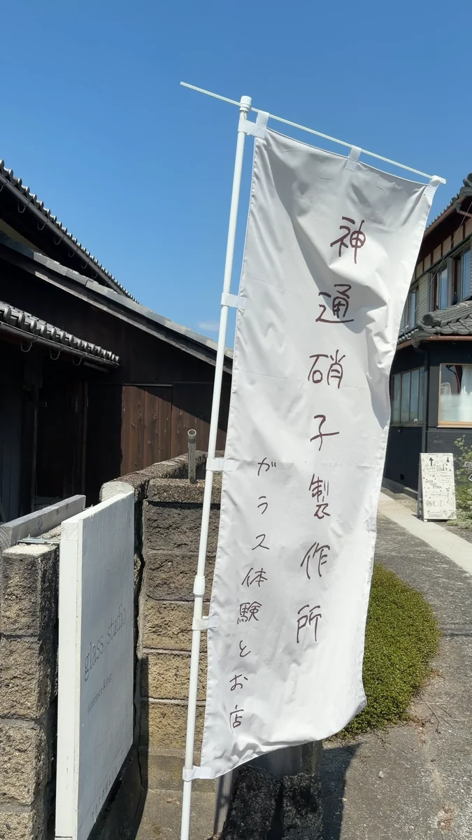 道沿いに立つのぼり。「ガラス体験とお店」とあります(左)/表札はガラスブロック。「神通硝子製作所 + calm life」と彫ってあります(右)