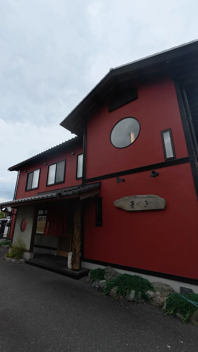 赤い壁の2階建て。壁に石の看板が掛かっています