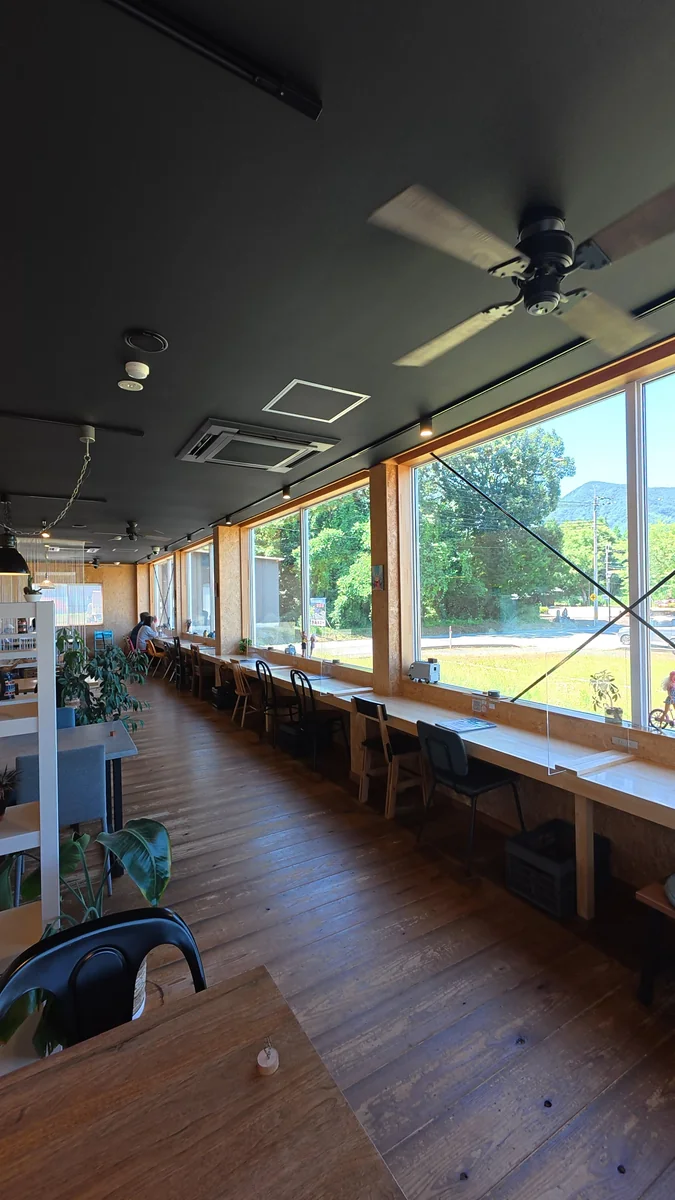 窓に面したカウンター席。外は山の緑（左）／土間に置かれた大きなソファ席（右）