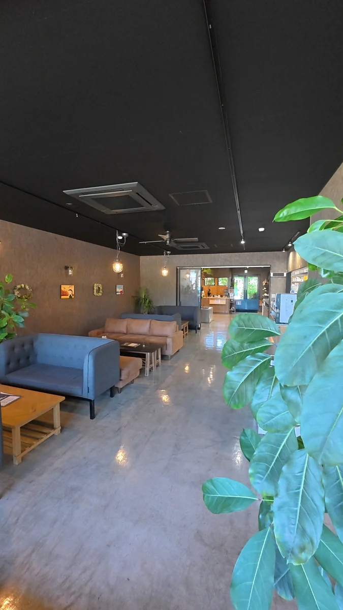 窓に面したカウンター席。外は山の緑（左）／土間に置かれた大きなソファ席（右）