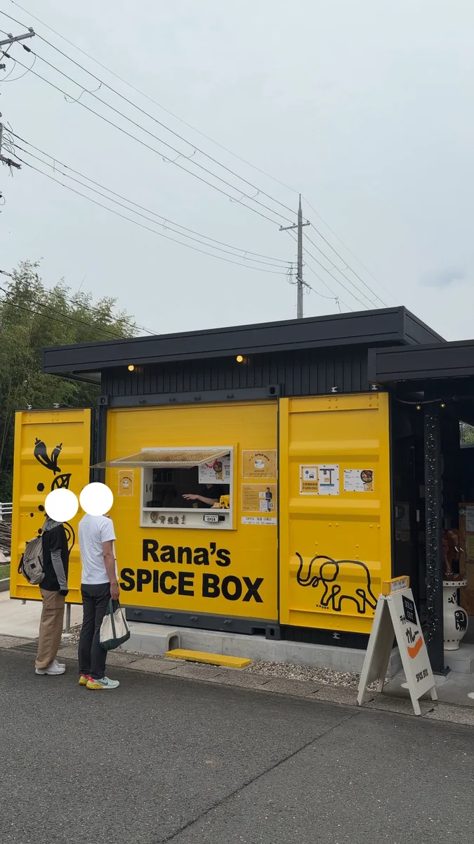 道沿いに置かれた黄色いコンテナ。屋根の下が店で、右手の奥がカーポートです