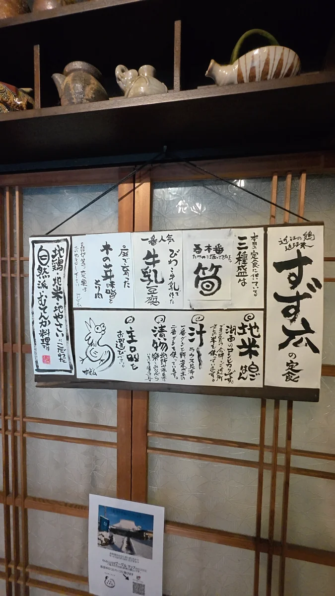 壁に掛かった手書きの品書き。三種盛の中身と、ごはん・汁・漬物の説明が書かれています